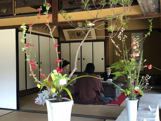 画像ファイル：「生け花展:2つの作品越しに見える宮崎兄弟の人形がうつる写真」の詳細を見る